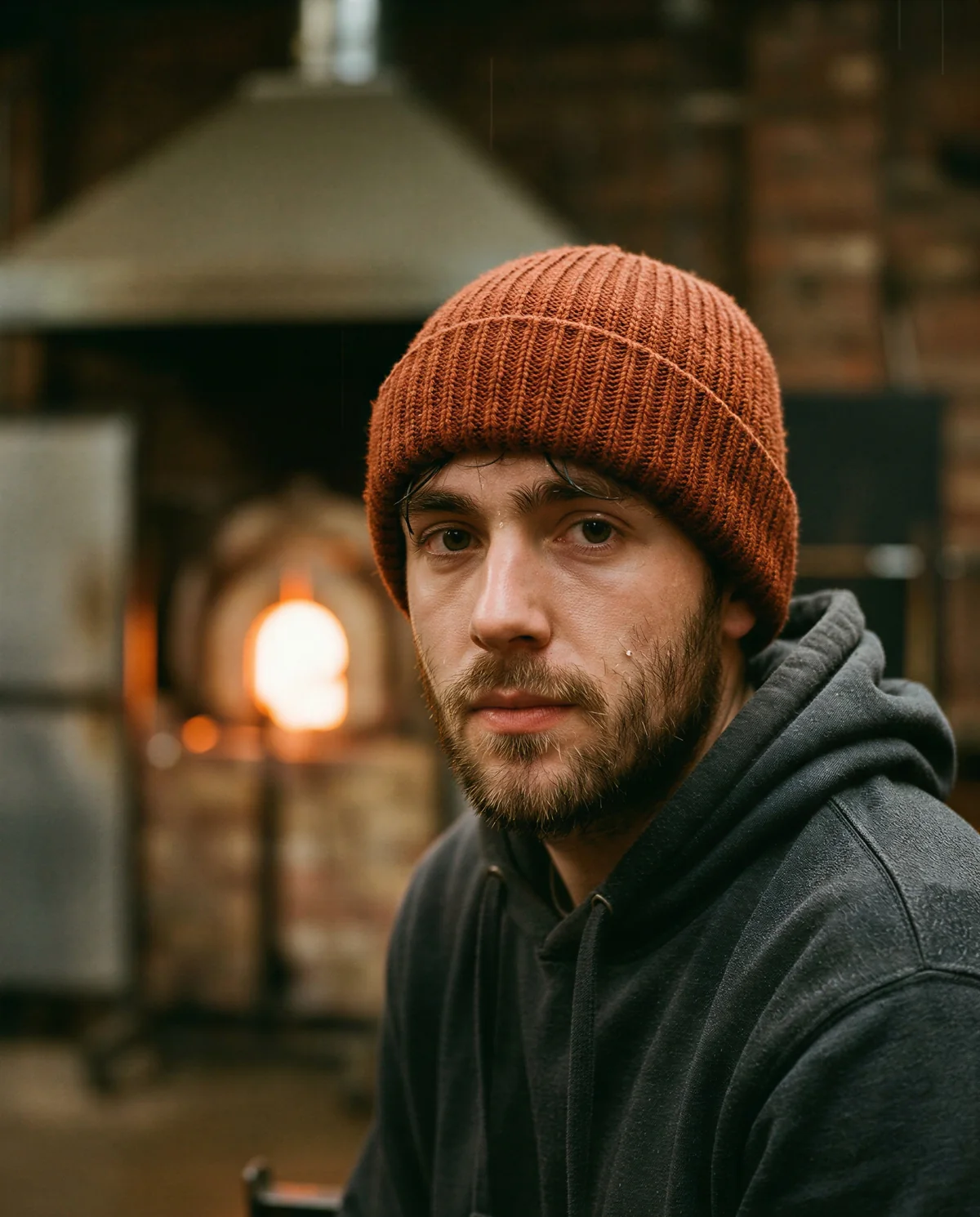 Portrait in burnt orange beanie beside a furnace